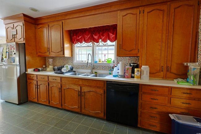 Kitchen with freestanding refrigerator, dishwasher, light countertops, and brown cabinetry | Image 6