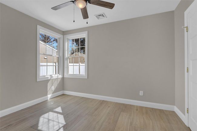 Empty room with ceiling fan, light wood-style floors, visible vents, and baseboards | Image 15