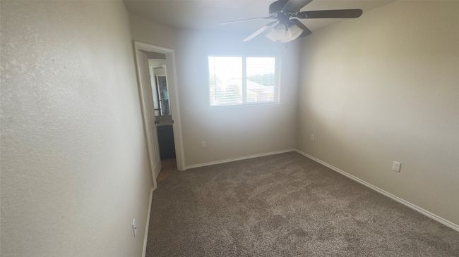 Empty room featuring a ceiling fan and dark colored carpet | Image 10