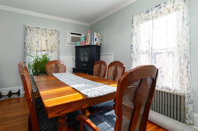 Dining space with an AC wall unit, radiator, ornamental molding, and hardwood / wood-style flooring | Image 7