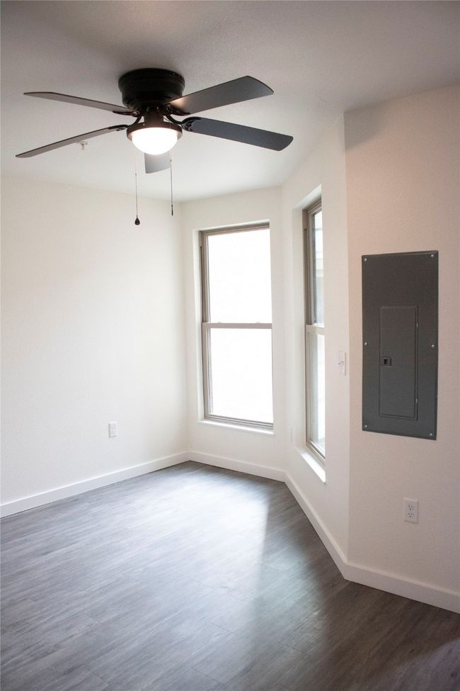 Unfurnished room featuring electric panel, a healthy amount of sunlight, a ceiling fan, and dark wood-type flooring | Image 5