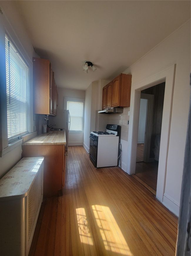 Kitchen with light countertops, light wood-type flooring, ventilation hood, gas range, and brown cabinetry | Image 5