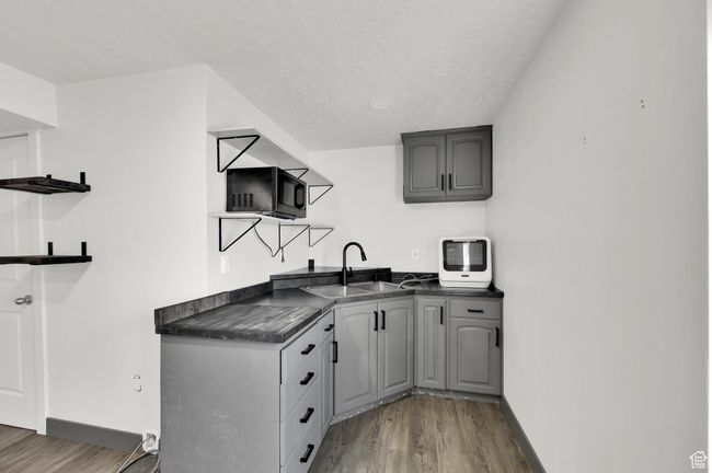 Kitchen with a sink, dark countertops, open shelves, and wood finished floors | Image 21