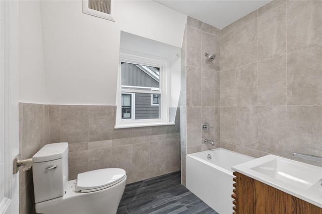 Full bathroom with visible vents, toilet, tile walls, shower / bathing tub combination, and vanity | Image 16