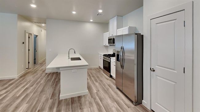 Kitchen featuring a sink, light wood-type flooring, white cabinetry, light countertops, and appliances with stainless steel finishes | Image 8