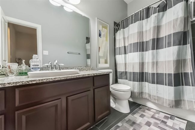 Second full bathroom features a modern design with a granite countertop, dark wood cabinetry, and a large mirror. It includes a tub/shower combo. | Image 26