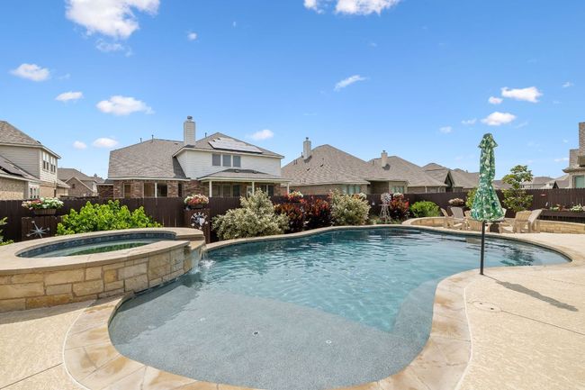 View of swimming pool featuring a fenced backyard, a patio area, a pool with connected hot tub | Image 9