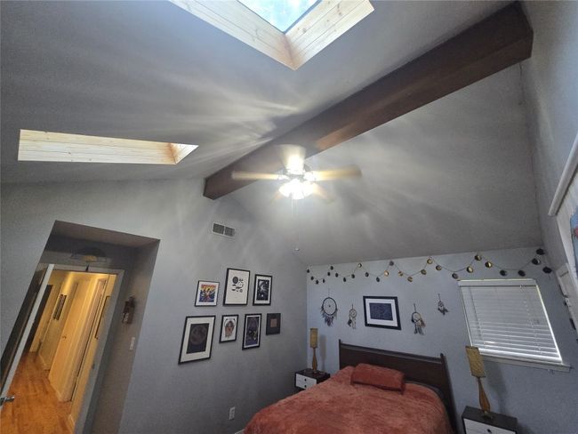 Bedroom featuring a skylight, vaulted ceiling, and ceiling fan | Image 13