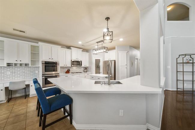 A quartz surfaced wraparound breakfast bar doubles as a serving area and provides a natural delineation between the living room & kitchen. | Image 14