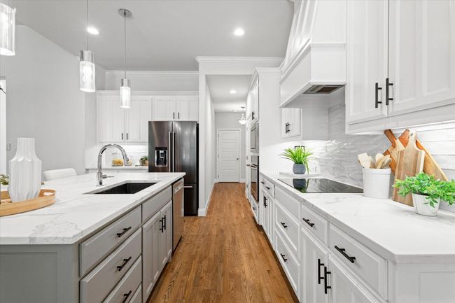 Kitchen featuring appliances with stainless steel finishes, custom exhaust hood, gray cabinetry, light wood-style flooring, and tasteful backsplash | Image 11