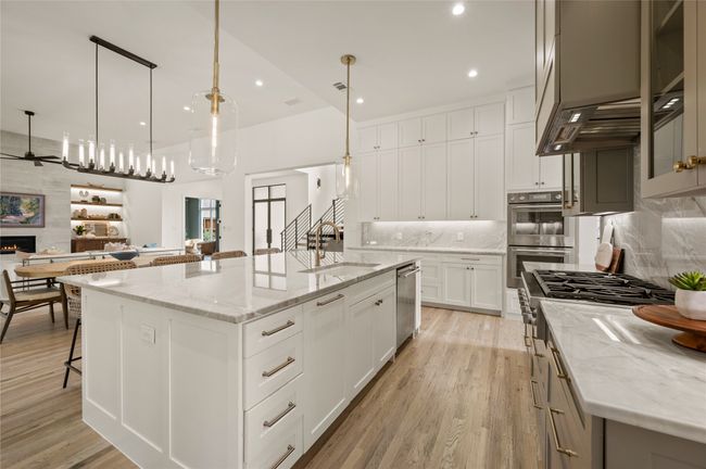 Thermador stainless steel appliances, custom range hood, backsplash, glass insert cabinets, and Quartzite | Image 10