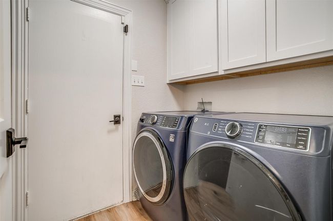 Laundry room featuring cabinet space, independent washer and dryer, and light wood finished floors | Image 34