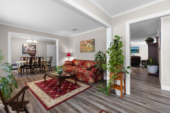 Living area with wood finished floors, ornamental molding, and a chandelier | Image 26