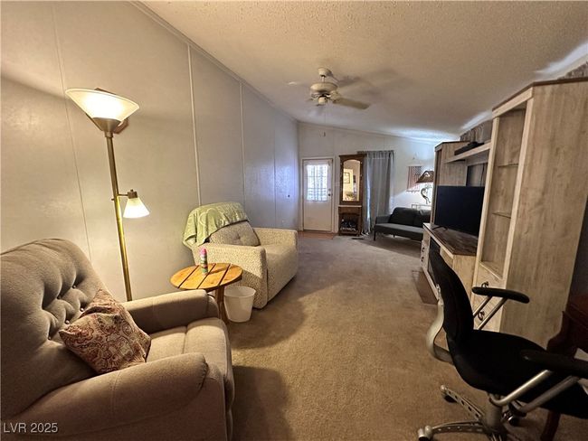 Carpeted living area featuring a ceiling fan, a textured ceiling, and lofted ceiling | Image 10