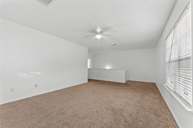 Unfurnished room featuring carpet, a ceiling fan, healthy amount of natural light, a textured ceiling, and baseboards | Image 22