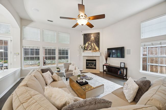Gather around the gas fireplace in this inviting family room, framed by a wall of windows that draw in natural light and provide views of the landscaped backyard. | Image 9