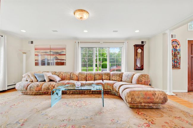 Living room featuring wood finished floors, ornamental molding, baseboard heating, recessed lighting, and decorative columns | Image 7