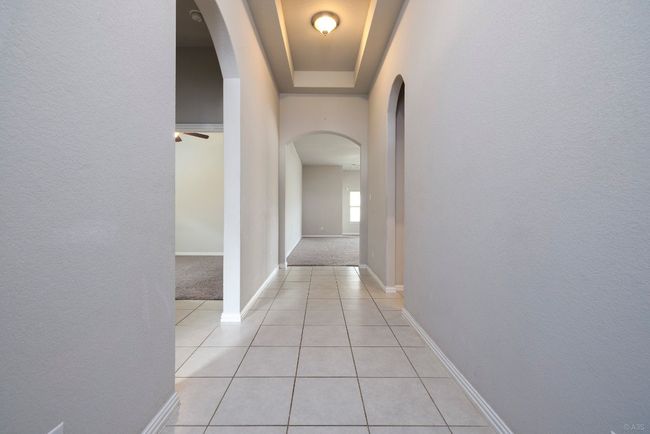 Corridor featuring arched walkways, light tile patterned flooring, and light colored carpet | Image 4