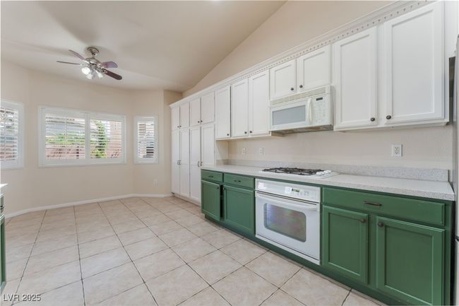 Kitchen featuring white appliances, green cabinets, light countertops, ceiling fan, and vaulted ceiling | Image 17
