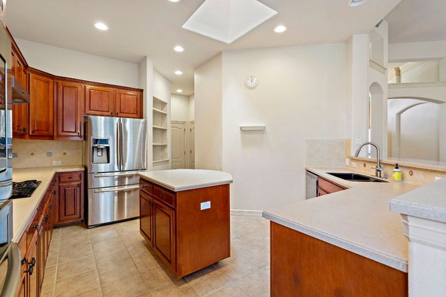 Kitchen with stainless steel appliances, a sink, arched walkways, a skylight, and decorative backsplash | Image 11