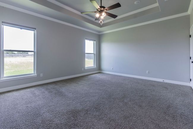 Spare room featuring a raised ceiling, ceiling fan, carpet flooring, and crown molding | Image 13