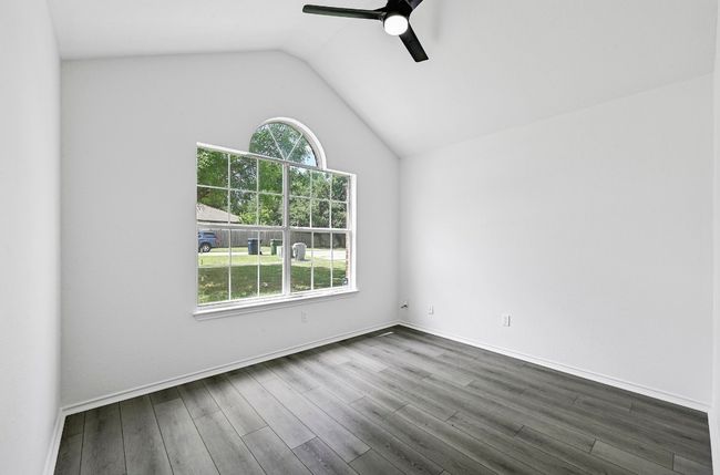 Empty room with healthy amount of natural light, ceiling fan, dark wood-style flooring, and vaulted ceiling | Image 22