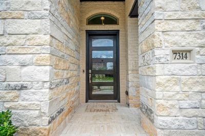 Approaching the front door you will see the beautiful brick and stone elevation, covered front porch, and an 8ft stained contemporary door! This home includes keyless entry and a smart door bell. | Image 3