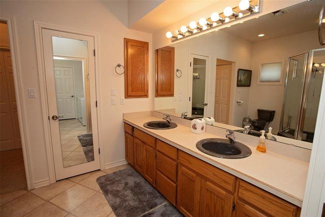 Bathroom featuring dual bowl vanity, separate washer and dryer, tile floors, and a shower with door | Image 28