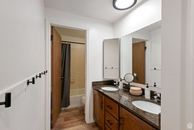Full bath featuring double vanity, wood finished floors, and shower / bathtub combination with curtain | Image 8