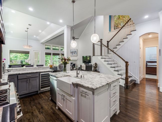 Kitchen featuring wine cooler, a sink, dark wood-style floors, light stone countertops, and arched walkways | Image 7