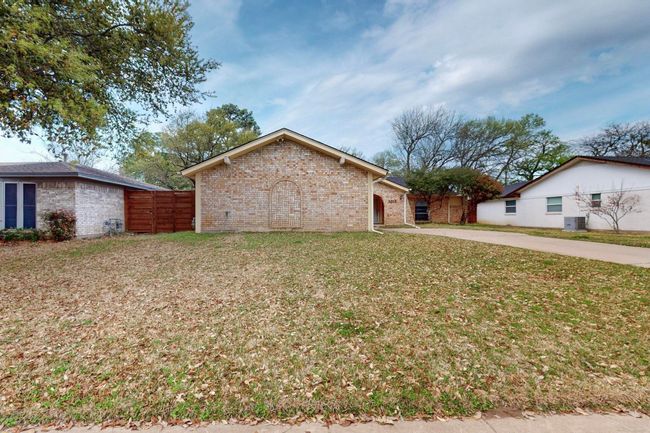View of side of property featuring brick siding, concrete driveway, fence, and a lawn | Image 4