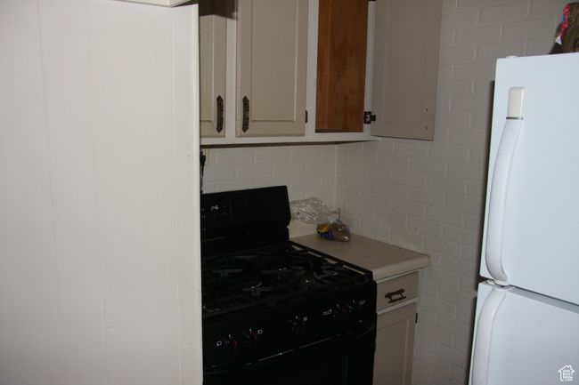 Kitchen featuring freestanding refrigerator, black gas range, light countertops, and tasteful backsplash | Image 18