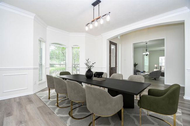As you enter your handsome front door with beveled glass and sidelite window, you are greeted with sky-high ceilings and your formal dining room to your right. Measuring 13' x 14', this elegant space with chair rail trim detailing is filled with natural light from the beautiful bay windows, creating an airy and inviting setting perfect for memorable dinners and celebrations. | Image 4
