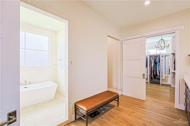 Full bathroom featuring a soaking tub, porcelain floors, a chandelier, vanity, walk-in closet private commode | Image 12