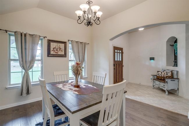 Dining room featuring arched walkways, a chandelier, vaulted ceiling, and wood finished floors | Image 10
