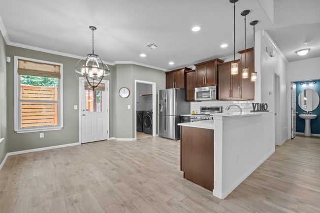 Kitchen featuring stainless steel appliances, separate washer and dryer, light countertops, ornamental molding, and tasteful backsplash | Image 13