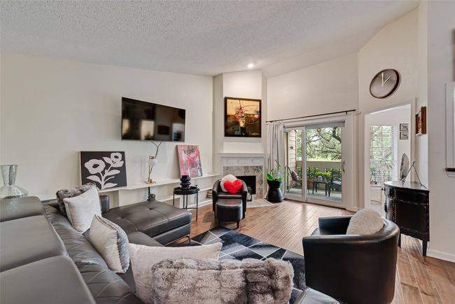 Living room featuring wood finished floors, a high end fireplace, a textured ceiling, and high vaulted ceiling | Image 5