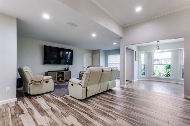 Living room with wood finished floors, crown molding, and recessed lighting | Image 5
