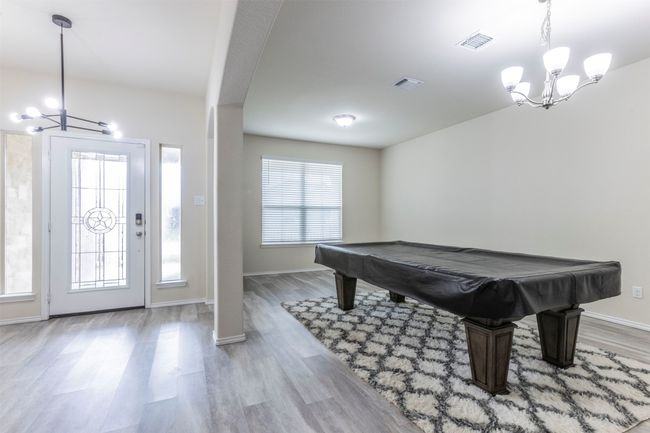 Playroom with plenty of natural light, visible vents, wood finished floors, and a notable chandelier | Image 11