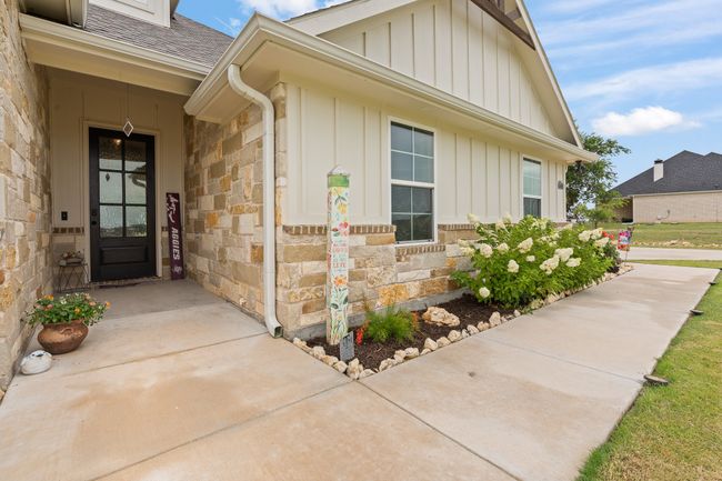 Doorway to property with board and batten siding, stone siding, and roof with shingles | Image 33