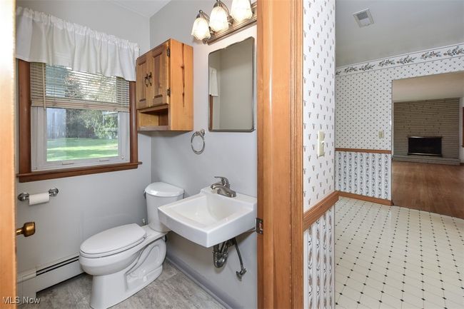 Half bathroom featuring wallpapered walls, visible vents, toilet, a sink, and baseboard heating | Image 30