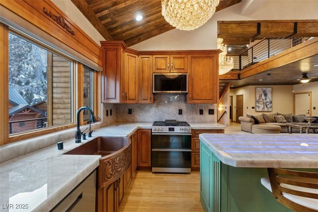 Kitchen featuring wooden ceiling, stainless steel appliances, a sink, light countertops, and tasteful backsplash | Image 34
