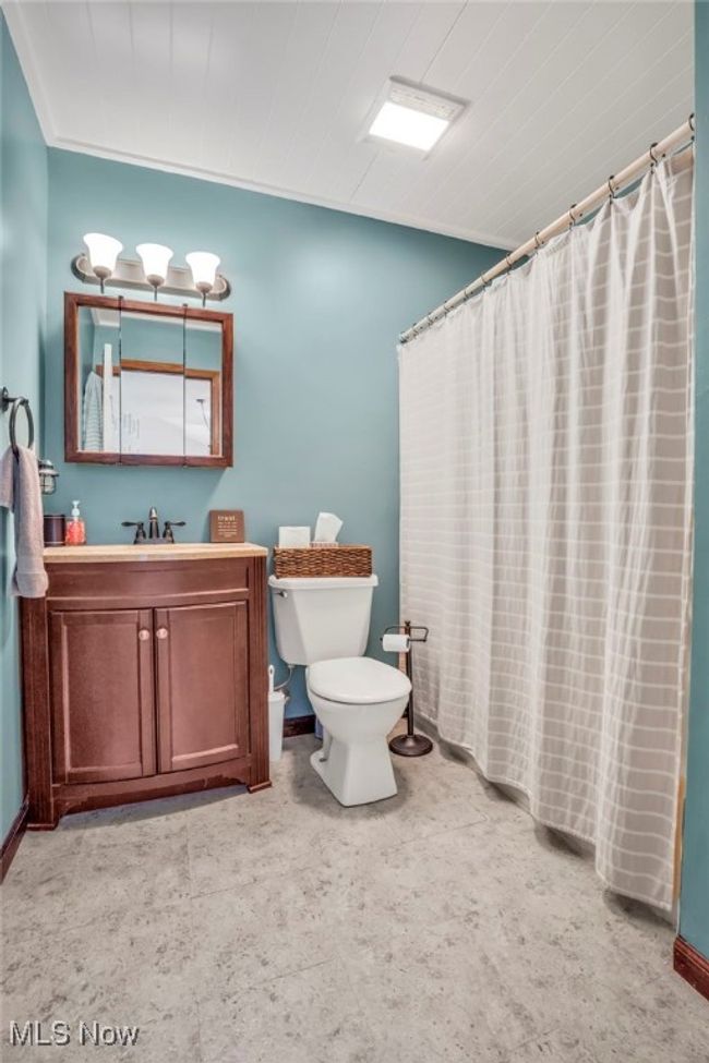 Bathroom with baseboards, toilet, a shower with curtain, and vanity | Image 15