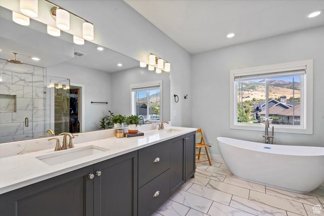 Primary full bathroom with marble look tile flooring, plenty of natural light, a shower stall, double vanity, and recessed lighting | Image 31