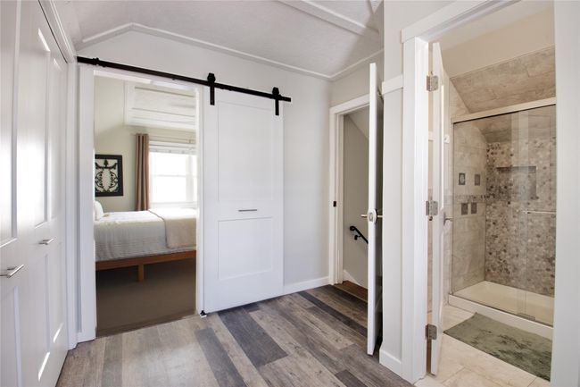 Full bath featuring a shower stall, lofted ceiling, ensuite bath, wood finished floors, and baseboards | Image 14