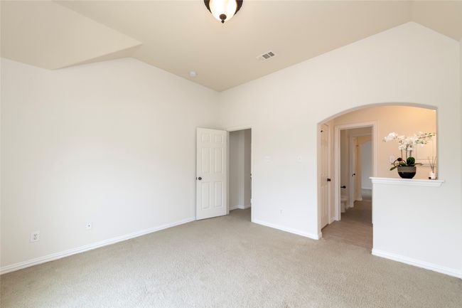 Unfurnished bedroom featuring lofted ceiling, light colored carpet, and arched walkways | Image 27