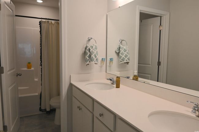 Bathroom with double vanity, tile patterned flooring, shower / bath combination with curtain, and recessed lighting | Image 27