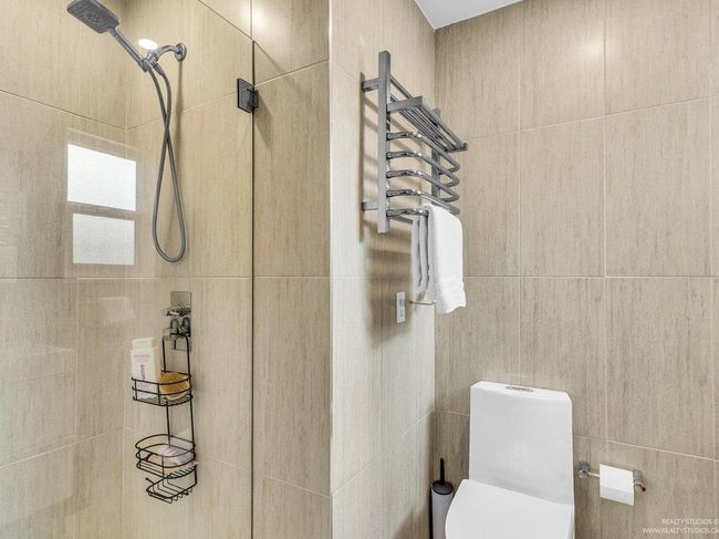 Full immaculate bathroom featuring a gorgeous shower, gleaming white sink and cabinet, toilet, and a luxurious towel warming rack. | Image 27