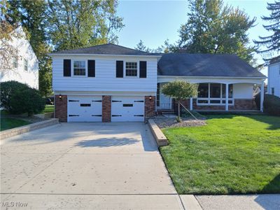 Split level home featuring a garage, a front lawn, and covered porch | Image 2