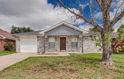 Ranch-style house with a front yard and a garage | Image 1